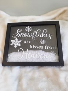 a framed sign that says snowflakes are kisses from heaven on the bed with white sheets