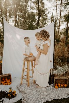 Mother and child embrace in a dreamy white sheet photoshoot, surrounded by oranges and flowers in Ocala, Florida. The warm colors and natural setting create a serene and inviting atmosphere, highlighting the beauty of their relationship. Perfect inspiration for photographers and a heartwarming Mother's Day gift idea. 
 #mommyandmephotoshoot #ocalaflorida #motherhoodphotography #orangesandflowers #whitesheetphotoshoot #familyphotography #mothersdaygiftidea White Sheet Backdrop, Sheet Backdrop, Fall Mini Shoot, Mommy And Me Photoshoot, Picnic Photo Shoot, Pumpkin Patch Photoshoot, Beauty Of Motherhood, Mommy And Me Photo Shoot, Eleven Eleven