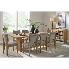 a dining room table and chairs in front of a window with a vase on it