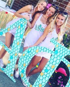 three girls are posing in front of a sign