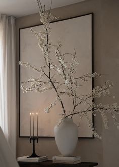 a vase filled with white flowers sitting on top of a table next to a candle