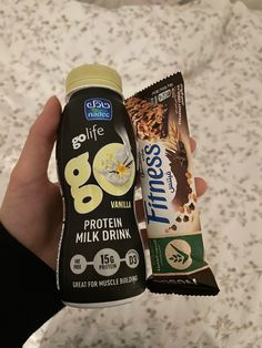 someone is holding up a protein bar and milkshake