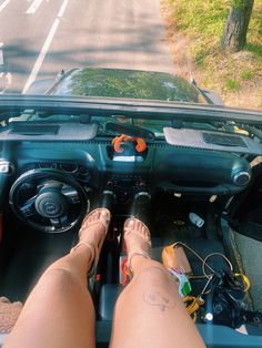 a woman is sitting in the driver's seat of a car with her feet on the dashboard