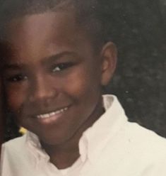 a young boy smiling and wearing a white shirt