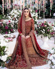 a woman in a red and gold bridal gown sitting on a flower covered floor