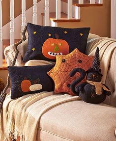 three decorative pillows sitting on top of a couch next to a stuffed animal and pumpkin