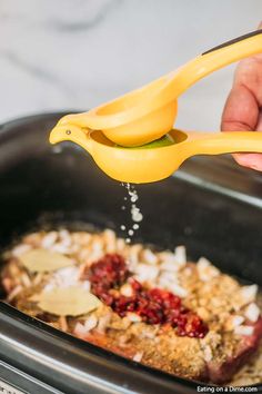 someone is sprinkling seasoning on food in the slow cooker with a yellow spatula