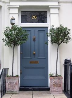 a blue front door with two planters on either side and the number 713