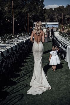 the back of a woman's dress as she walks down an aisle with tables and chairs