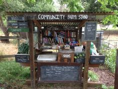 an outdoor book stand with lots of books on the shelves and chalkboard signs above it