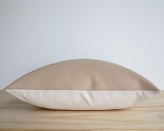 a pillow on a wooden table with a white wall in the backgrouund