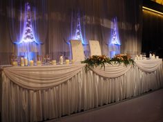 a table set up with candles and flowers on it for a wedding reception at night