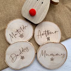 four wood slices with names on them sitting next to a teddy bear and other decorations