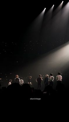 a group of people standing on top of a stage in front of bright spotlights