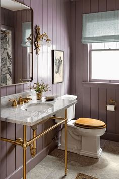 a bathroom with purple walls and gold fixtures