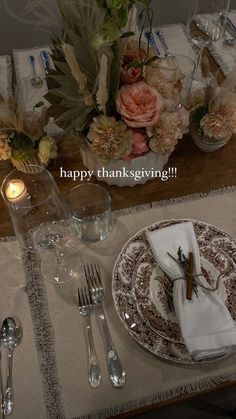 the table is set for thanksgiving dinner with flowers and candles