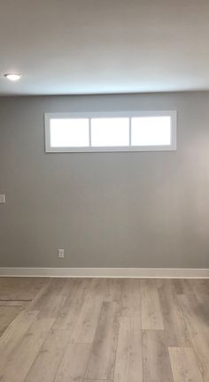 an empty room with hard wood floors and gray walls