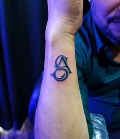 a man with a tattoo on his arm holding up the letter s in front of him