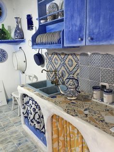 a kitchen with blue and white tiles on the counter tops, cabinets, and sink