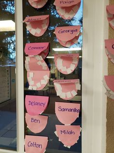 pink paper cutouts with names on them hanging from a window