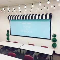 an empty classroom with tables and chairs in front of a large projection screen that says ecolie de france