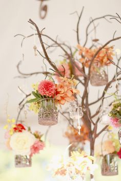 an arrangement of flowers in vases hanging from a tree