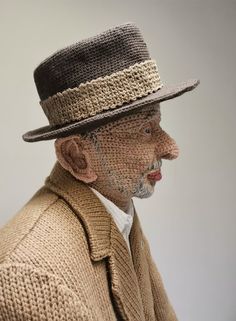 an old man wearing a hat and coat with a knitted sweater around his neck