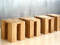 four wooden stools lined up against a wall