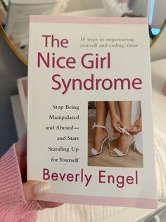 the nice girl syndrome book is being held by a woman's hand with her shoes on