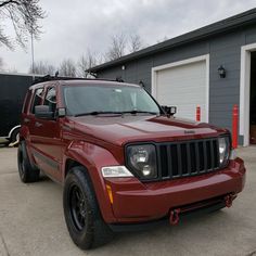 a red jeep parked in front of a garage