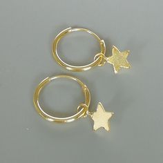 A PAIR of sterling silver hoops dipped in gold. Comes with a tiny star charm. The charm is multipurpose and can be used with a neck or bracelet chain too. Dimension: Hoop- 12x1 mm Charm- 5x5 mm Drop length- 18mm Price listed is for ONE PAIR These are made of 925 hypoallergenic sterling silver plated in gold. Most of my pieces come with a 925 stamp. Can be packaged in a gift box. I can include a personal message from you if needed You are welcome to contact me at... bhavnakwintra1956@gmail.com Fo Dainty Star-shaped Hoop Earrings For Everyday, Dainty Hoop Earrings With Star Charm, Dainty Hoop Earrings With Charms, Celestial Huggie Hoop Earrings For Everyday, Minimalist Dangle Hoop Earrings With Star Charm, Minimalist Hoop Jewelry With Star Charm, Celestial Hoop Earrings With Star Charm For Everyday, Everyday Small Hoop Star Charm Jewelry, Celestial Star-shaped Hoop Earrings For Everyday