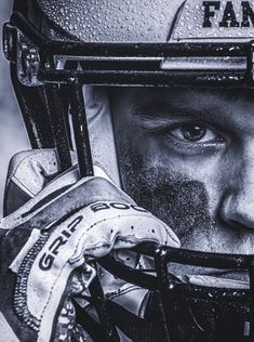 a black and white photo of a man wearing a football helmet with rain drops on his face