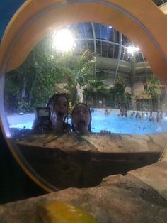 two people are reflected in a mirror at the same time as they stand near a swimming pool