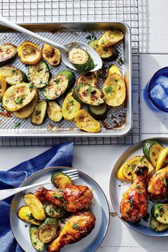 two plates with chicken, zucchini and squash on them next to a baking sheet