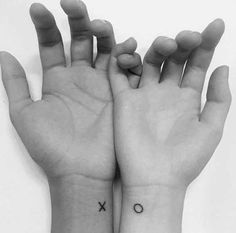 two hands with small tattoos on them