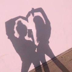 the shadow of two people standing next to each other in front of a white wall