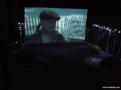 a person in a dark room with a screen on the wall and lights behind them