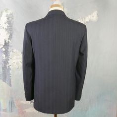 "This navy blue double-breasted blazer has notch lapels and padded shoulders, and closes in the front with one button (four in total show on the front). Three buttons decorate each sleeve cuff. The dark blue wool-blend jacket has three pockets on the front, and is fully lined in a navy blue satin viscose fabric (with two inner pockets). The fabric has a double pinstripe pattern, with a textured chevron herringbone running vertically as well. Brand label: Turo (Made in Finland) Size: 40 US/UK Mat Mens Sport Coats, Black Tuxedo Jacket, Pinstripe Blazer, Pinstripe Pattern, Mens Sport Coat, Wool Blend Jacket, Tuxedo Jacket, Leather Trench Coat, Brand Label