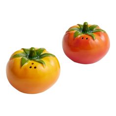 two plastic tomatoes with green leaves on them