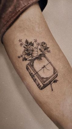 a tattoo on the leg of a woman with flowers and an old tv in it