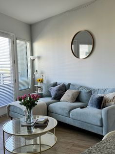 a living room filled with furniture and a round mirror on the wall over a coffee table