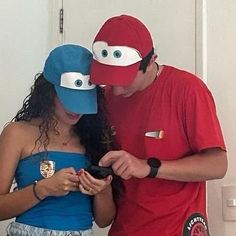 a man and woman in costumes looking at a cell phone