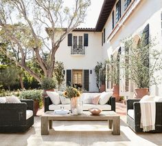 an outdoor living area with wicker furniture and potted plants on the patio table