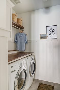 a washer and dryer sitting in a room next to a shelf with pictures on it