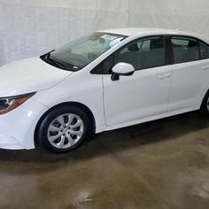 a white car parked in a garage next to a wall with a sign on it