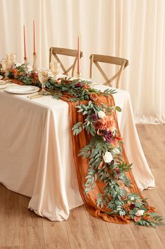 the table is set with an orange runner and flowers on it, along with candles