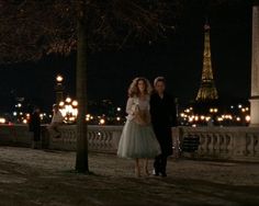 a man and woman standing next to each other in front of the eiffel tower