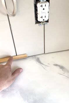 a hand is pointing at an electrical outlet