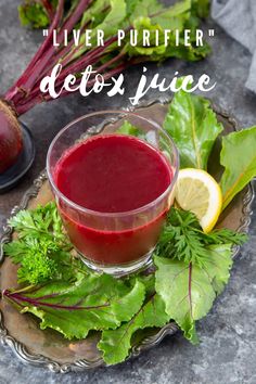 beet juice in a small glass bowl on a plate with fresh greens and lemon wedges