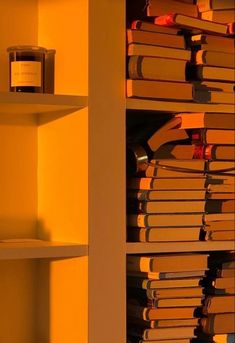 a book shelf filled with lots of books next to a can of wine and a candle